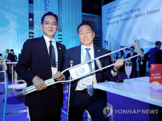 부상으로 목발을 짚고 참석한 최태원 SK그룹 회장(오른쪽)과 이재용 삼성전자 회장이 21일(현지시간) 프랑스 파리 이시레몰리노의 한 스포츠센터에서 열린 2030 부산세계박람회 공식 리셉션에서 함께 목발을 들고 미소짓고 있다. 연합뉴스